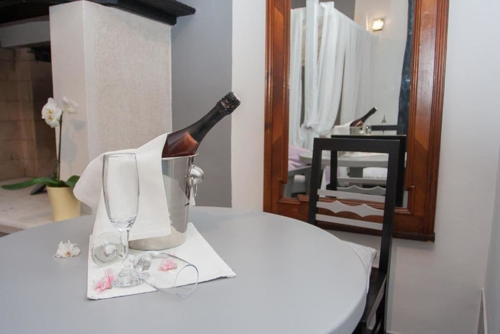A table with a bottle of champagne, a glass, and a napkin with flowers.