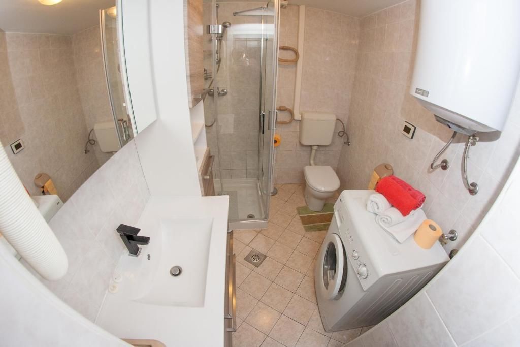 Une petite salle de bain comprenant une douche, des toilettes et un lave-linge.