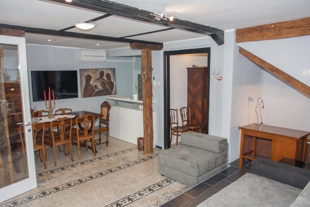 Uma área de refeições com mesa e cadeiras de madeira, um sofá cinza e uma pequena mesinha de madeira.