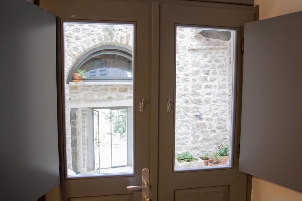 A double door with a stone wall view, a small balcony with plants, and a door handle.