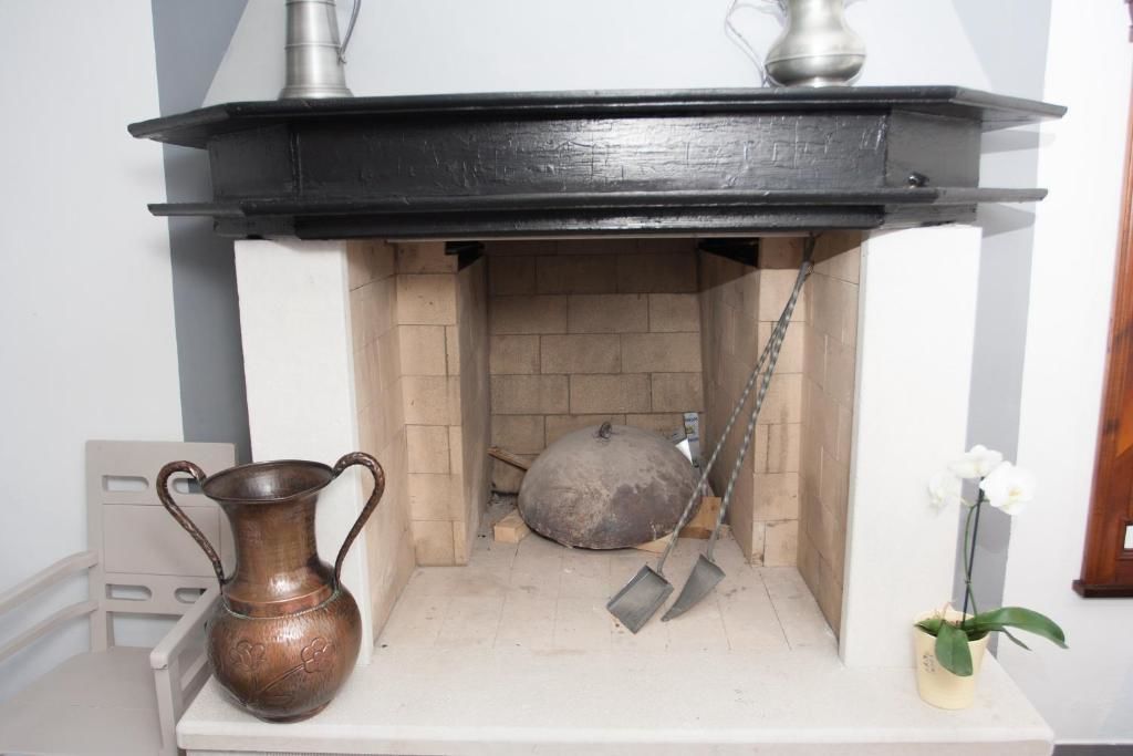 Una chimenea con repisa negra, una olla de metal y una pala.