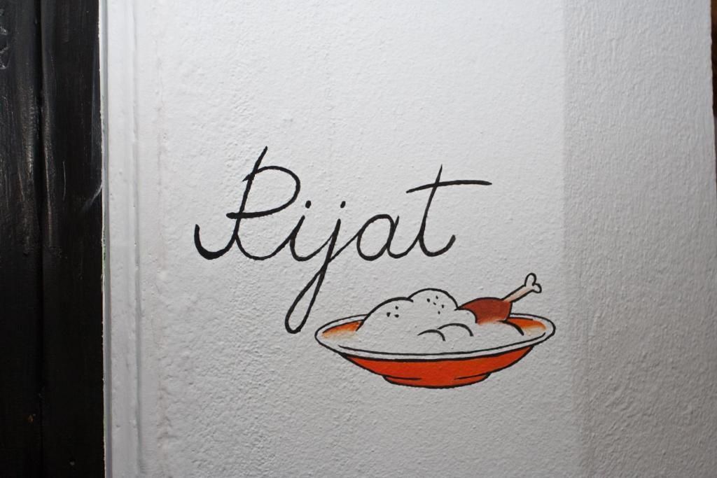 A wall with the word "Pijat" and a bowl of food.