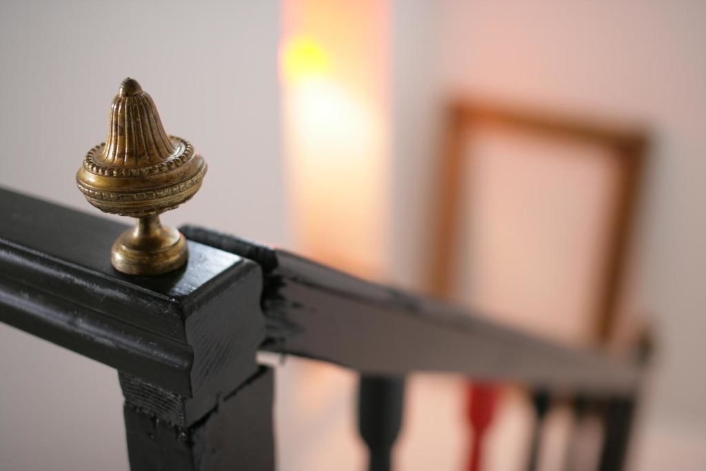 A close-up of a brass finial on a black metal railing.
