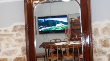 A mirror with a wooden frame reflecting a dining area with a TV mounted on the wall.