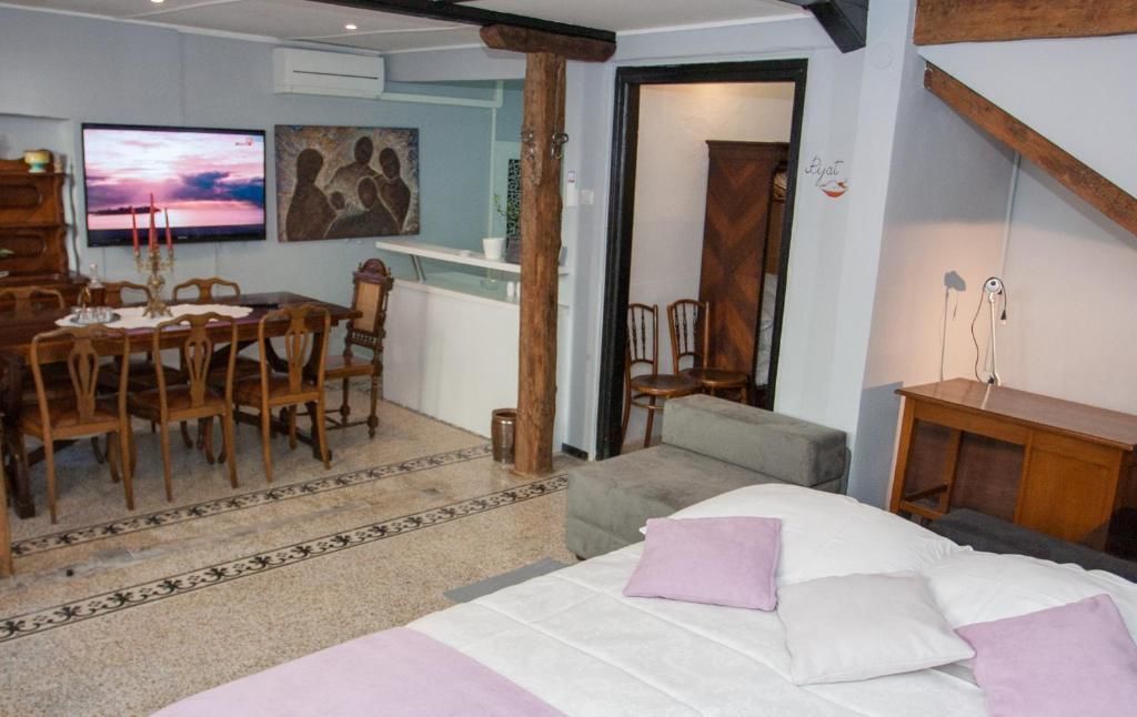 A room with a bed, a desk, a chair, a television, and a painting on the wall.