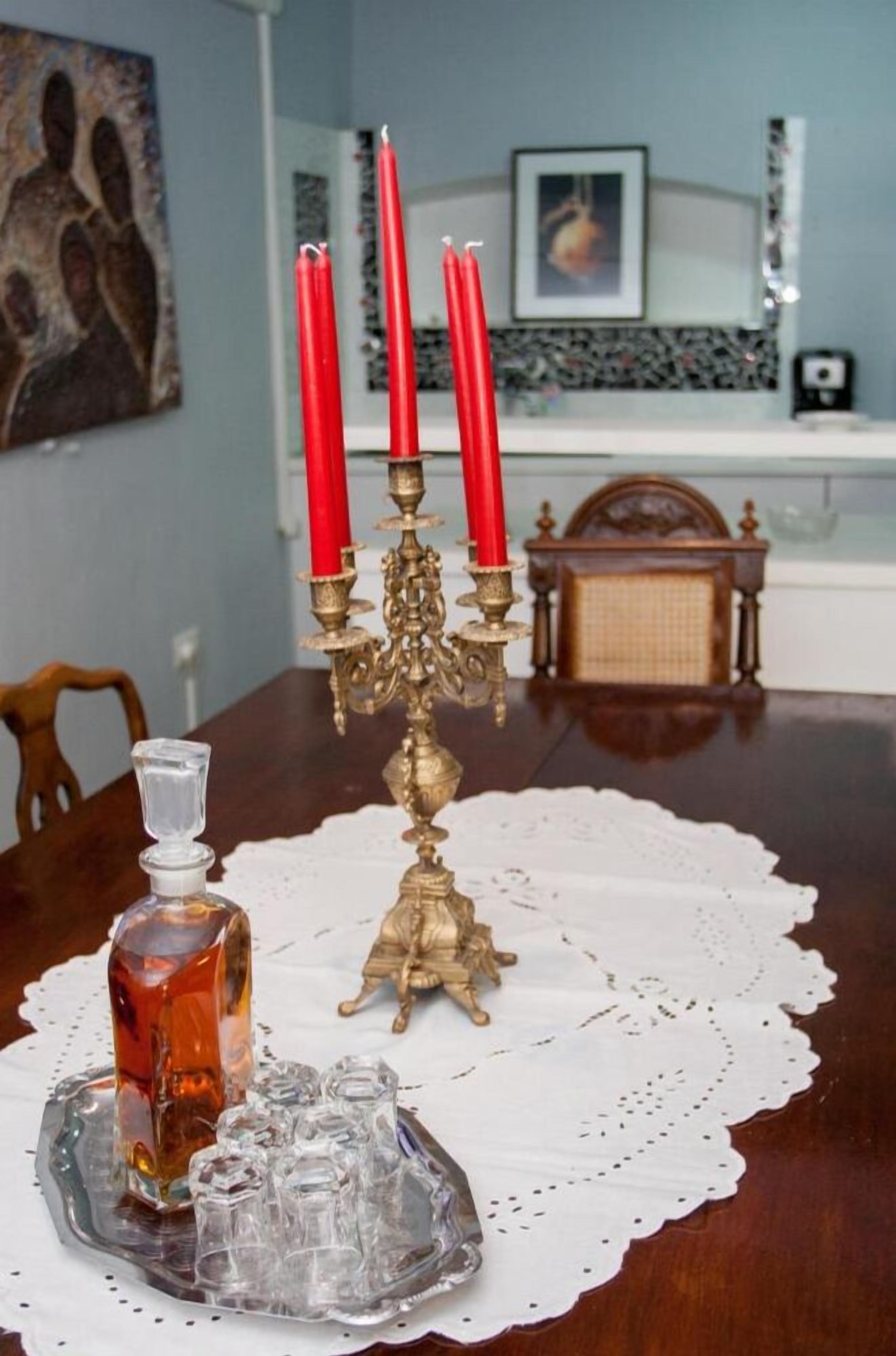 Una mesa de comedor con un candelabro decorativo, una jarra de cristal y una bandeja con vasos.