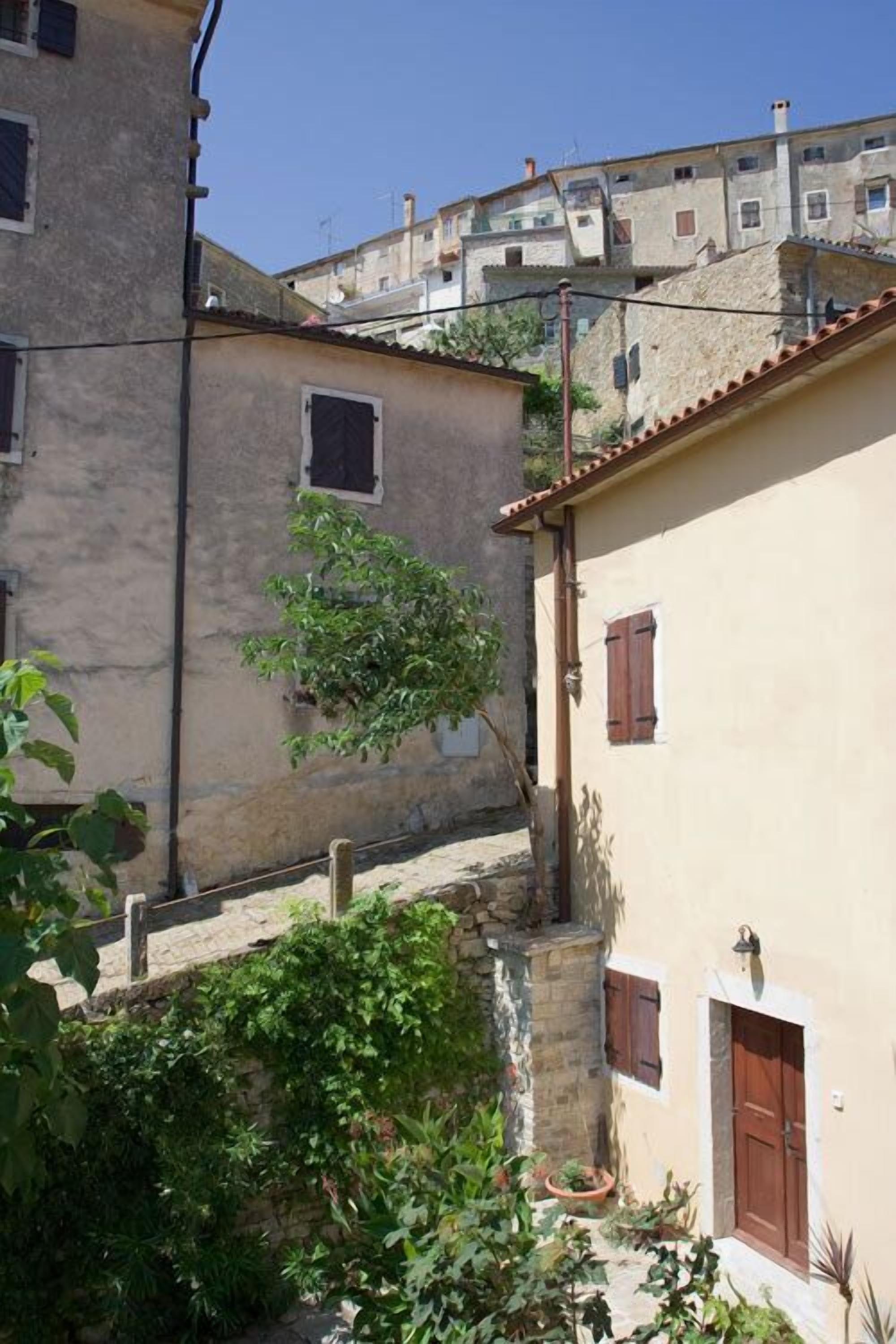 A narrow street with buildings on both sides, featuring stone walls and wooden shutters.