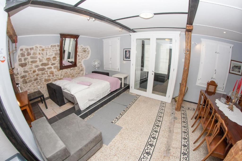Un dormitorio con pared de piedra, una cama, un escritorio y una zona de comedor con sillas.