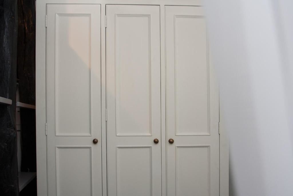 Un conjunto de tres puertas blancas con manijas de madera, probablemente dando acceso a una habitación o área de almacenamiento.