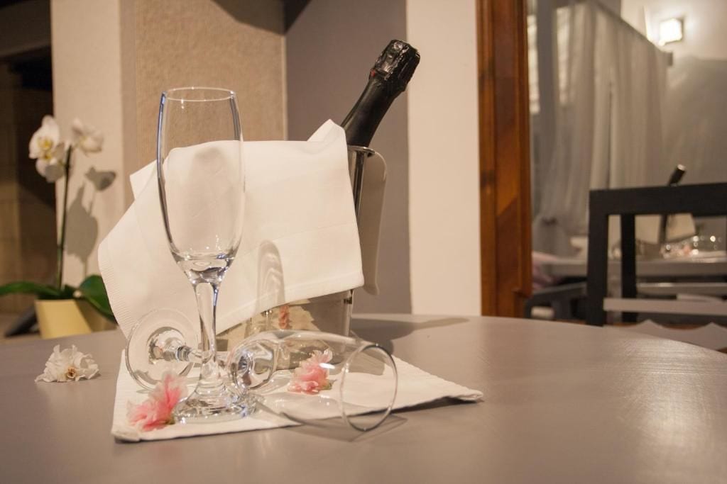 A table with a wine glass, a bottle, and a napkin holder.