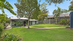 A residential backyard with a covered patio, a grassy lawn, and a wooden fence. - 20 Roslin St Moffat Beach QLD (MOFFAT BEACH)