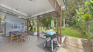 A patio with a grill, a dining table, and chairs. - 20 Roslin St Moffat Beach QLD (MOFFAT BEACH)