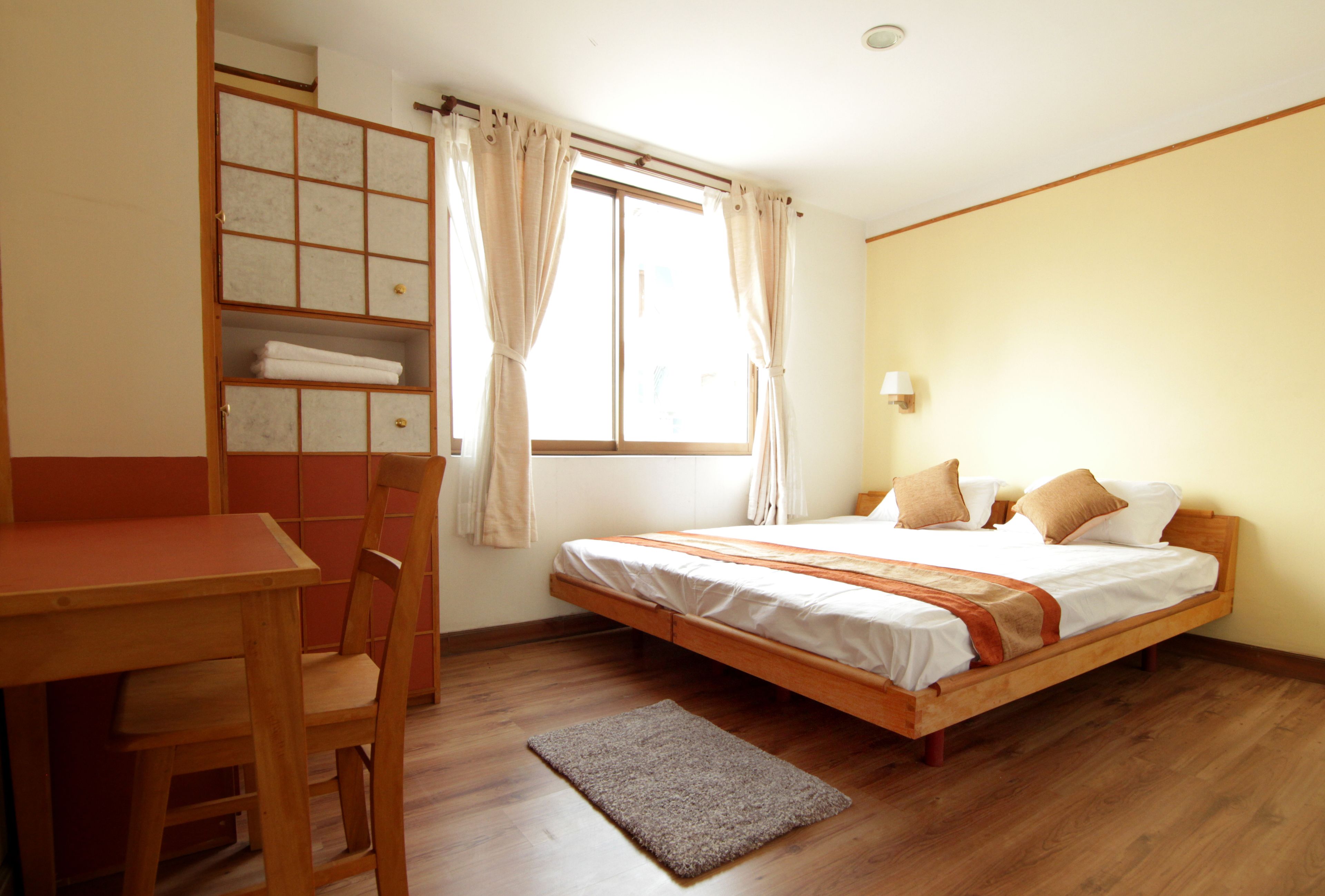 A bedroom with a wooden bed, a desk, and a chair.