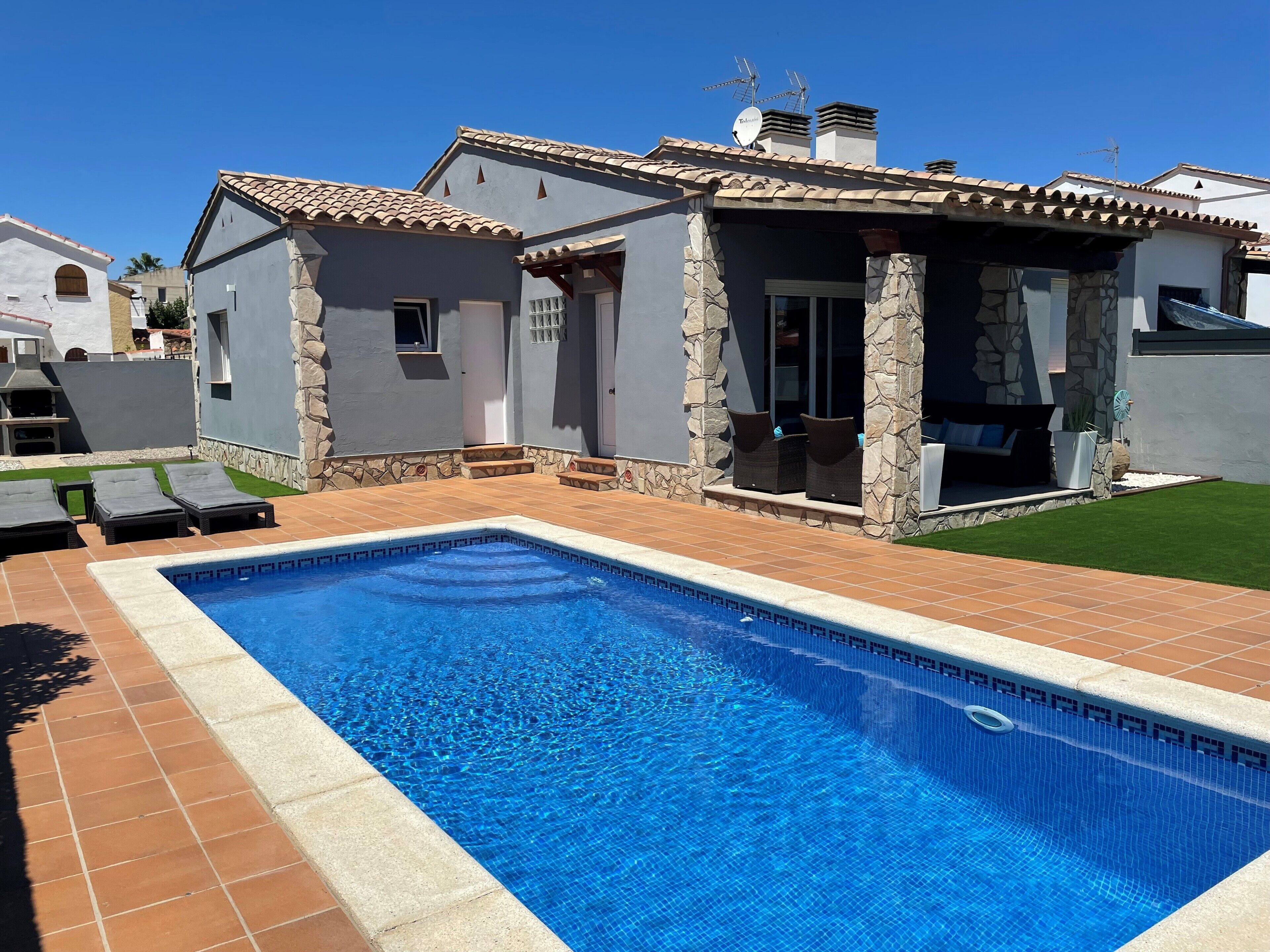 A modern house with a swimming pool, stone pillars, and outdoor seating.