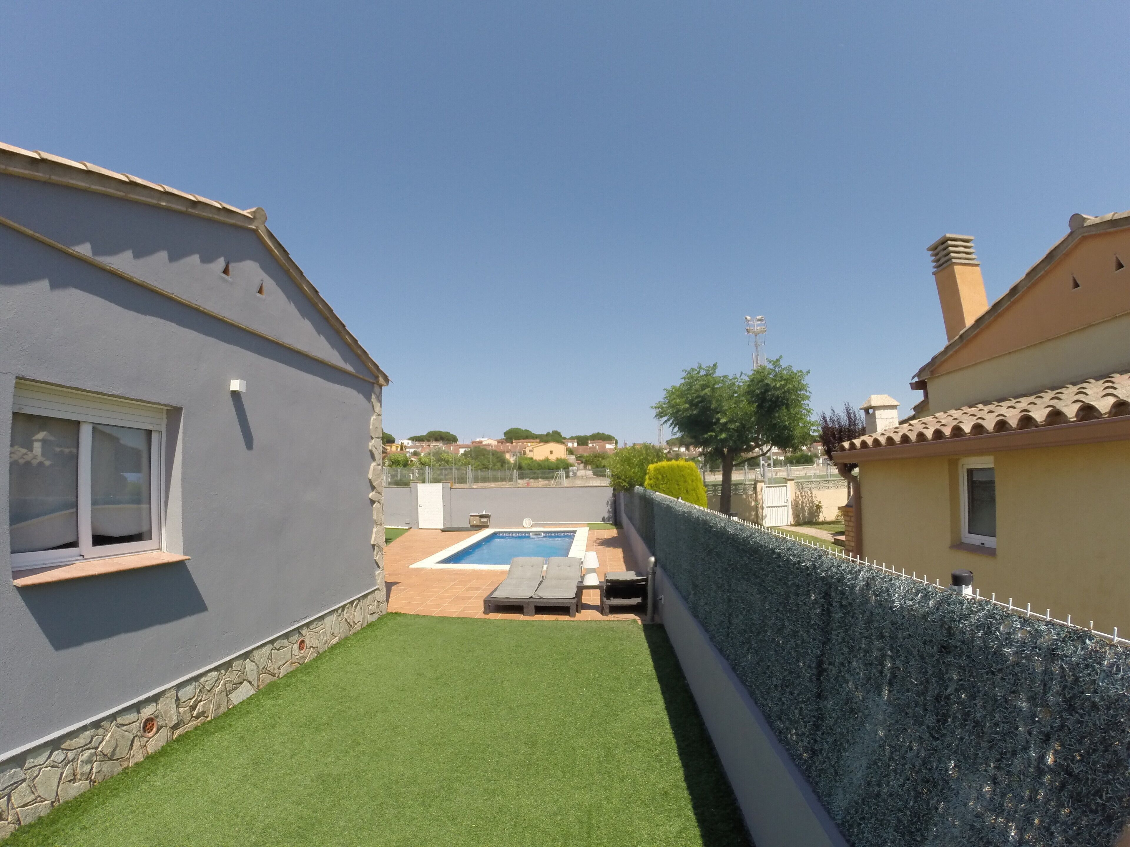 A residential property with a swimming pool, a stone wall, and a view of neighboring houses.
