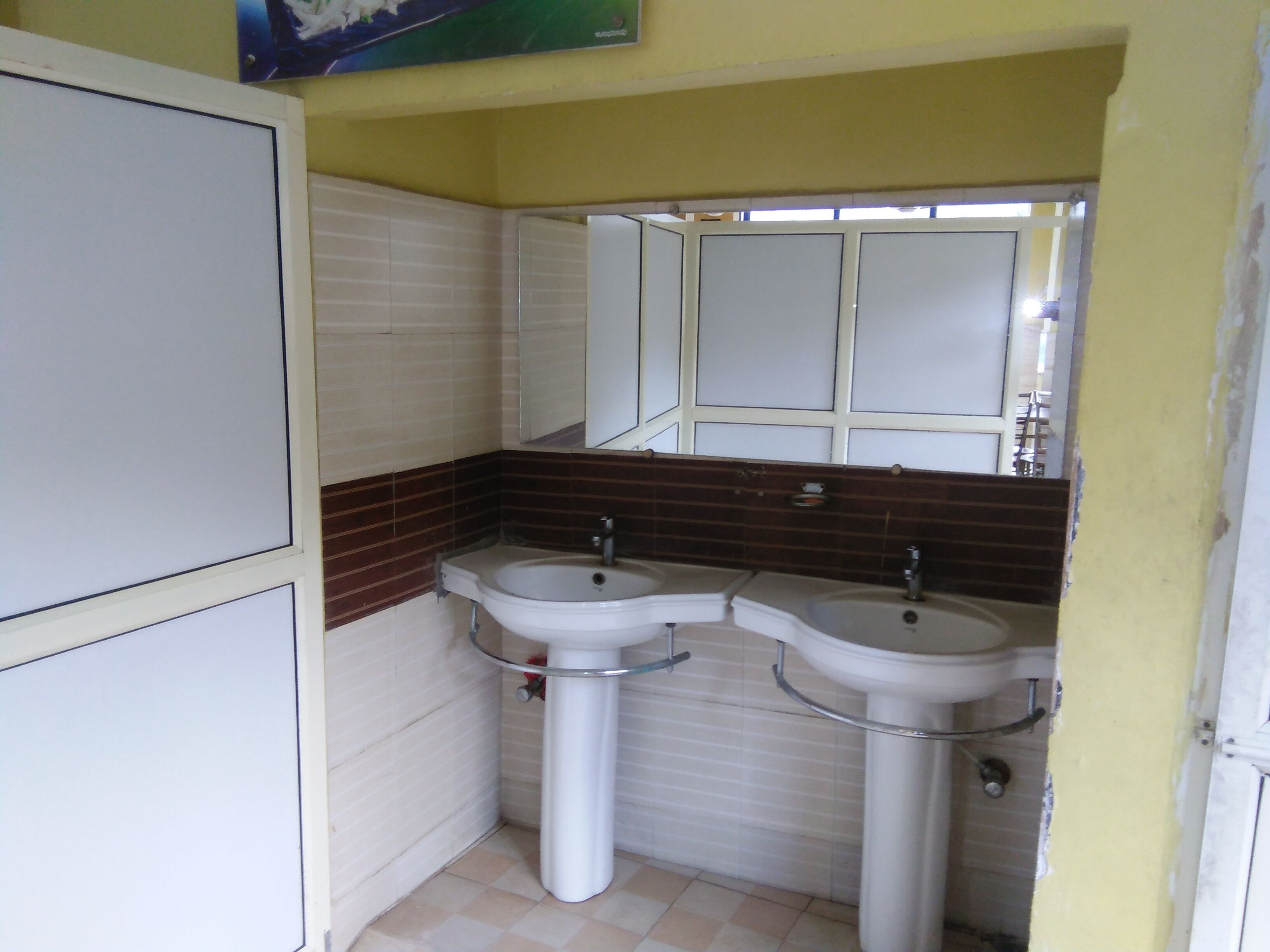 Un baño con dos lavamanos, un espejo y una ventana.
