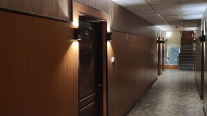 A hallway with wooden paneling, a tiled floor, and a door marked with the number 108. - Hotel Chakasha Govindam (Devaprayag)