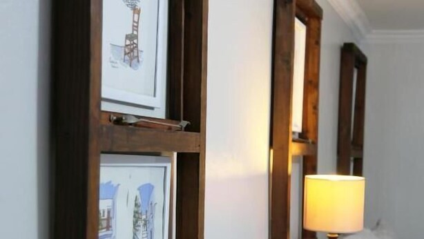 Une chambre avec un lit, une table de chevet et des œuvres d’art encadrées accrochées au mur.
