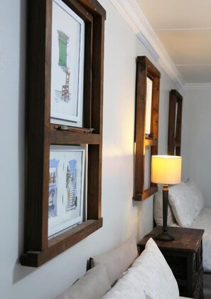 A room with a bed, a nightstand, and framed artwork on the wall.