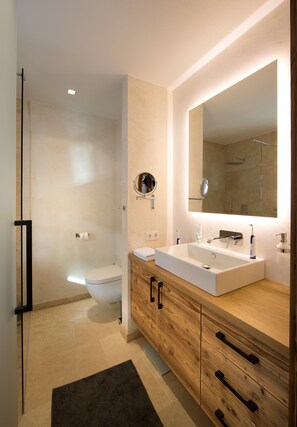 Une salle de bain moderne avec un meuble-lavabo en bois, un grand miroir, une douche et des toilettes.