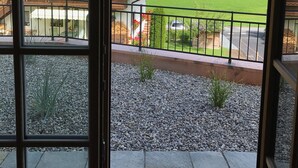 A view from a window overlooking a green field, a building with a red roof, and a mountain range.