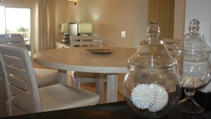 A dining area with a round table, chairs, and clear glass containers with white decorative items.
