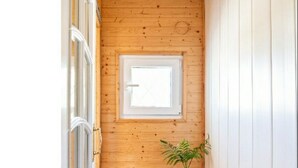 A narrow hallway with wooden walls, a potted plant, and a window.