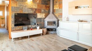 A modern living room with a stone wall, a fireplace, a TV, and a white cabinet.