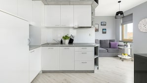 A modern kitchen with white cabinets, a grey countertop, and a grey sofa in the adjacent living area. - Comfortable 36 m² apartment with balcony, bedroom and modern furnishings. (Świnoujście)