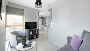 A modern living room with a grey sofa, a small coffee table, a TV, and a bookshelf. - Comfortable 36 m² apartment with balcony, bedroom and modern furnishings. (Świnoujście)