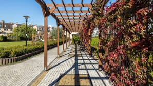 A covered walkway with a wooden pergola, brick pavement, and a wall with climbing plants. - Comfortable 36 m² apartment with balcony, bedroom and modern furnishings. (Świnoujście)