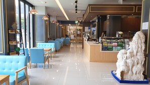 A modern cafe with blue cushioned seating, a wooden counter with a beverage display, and a decorative white rock sculpture. - Daedunsan Hotel (Wanju)