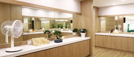 A reception area with a wooden counter, a standing fan, and potted plants.