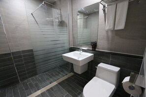 A modern bathroom with a glass shower enclosure, a white sink, and a toilet. - Daedunsan Hotel (Wanju)
