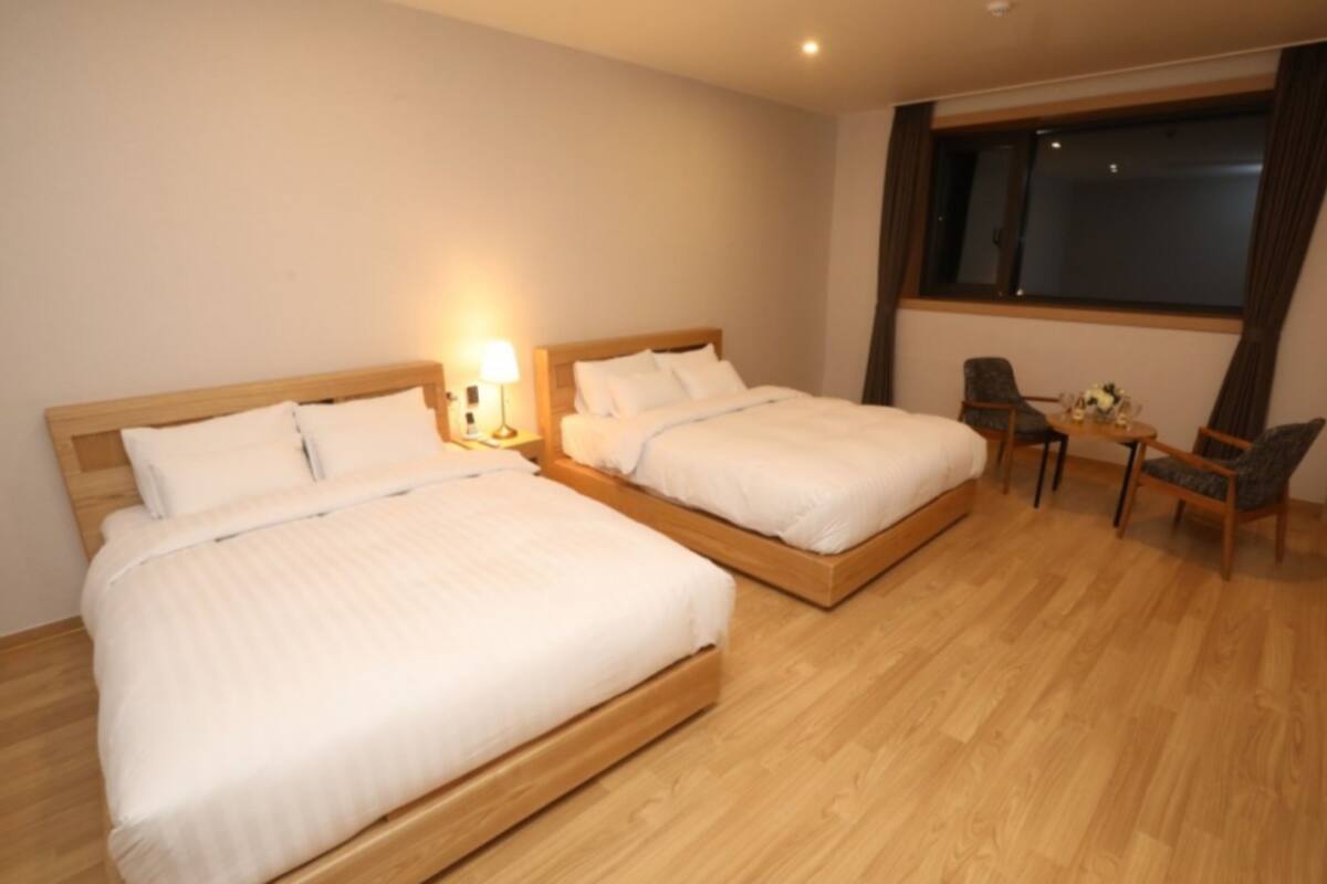 A hotel room with two beds, a desk, and a chair.