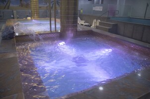 Un jacuzzi con piso de azulejos y separador de vidrio.