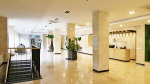 A hotel lobby with a reception desk, a staircase, and potted plants. - Daedunsan Hotel (Wanju)