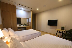 A hotel room with two beds, a desk, a chair, a TV, and a small table with a plant. - Daedunsan Hotel (Wanju)