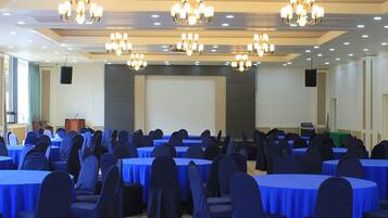 Un salón de conferencias con mesas redondas, manteles azules y sillas oscuras.