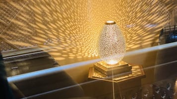 A decorative lamp with intricate patterns on a stand, set against a backdrop of ornate wall designs.