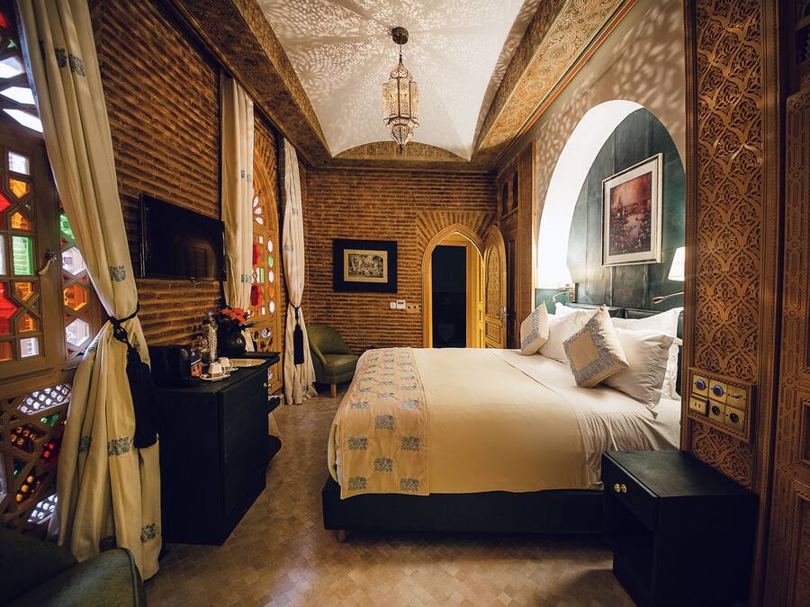Une chambre traditionnelle avec un lit, un bureau et une chaise. Un lustre est suspendu au plafond.