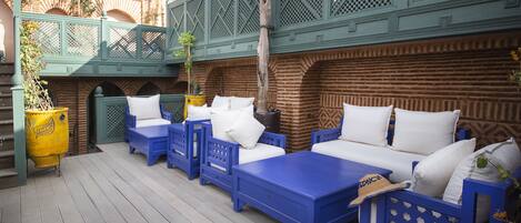 A wooden deck with blue furniture and a green lattice structure.
