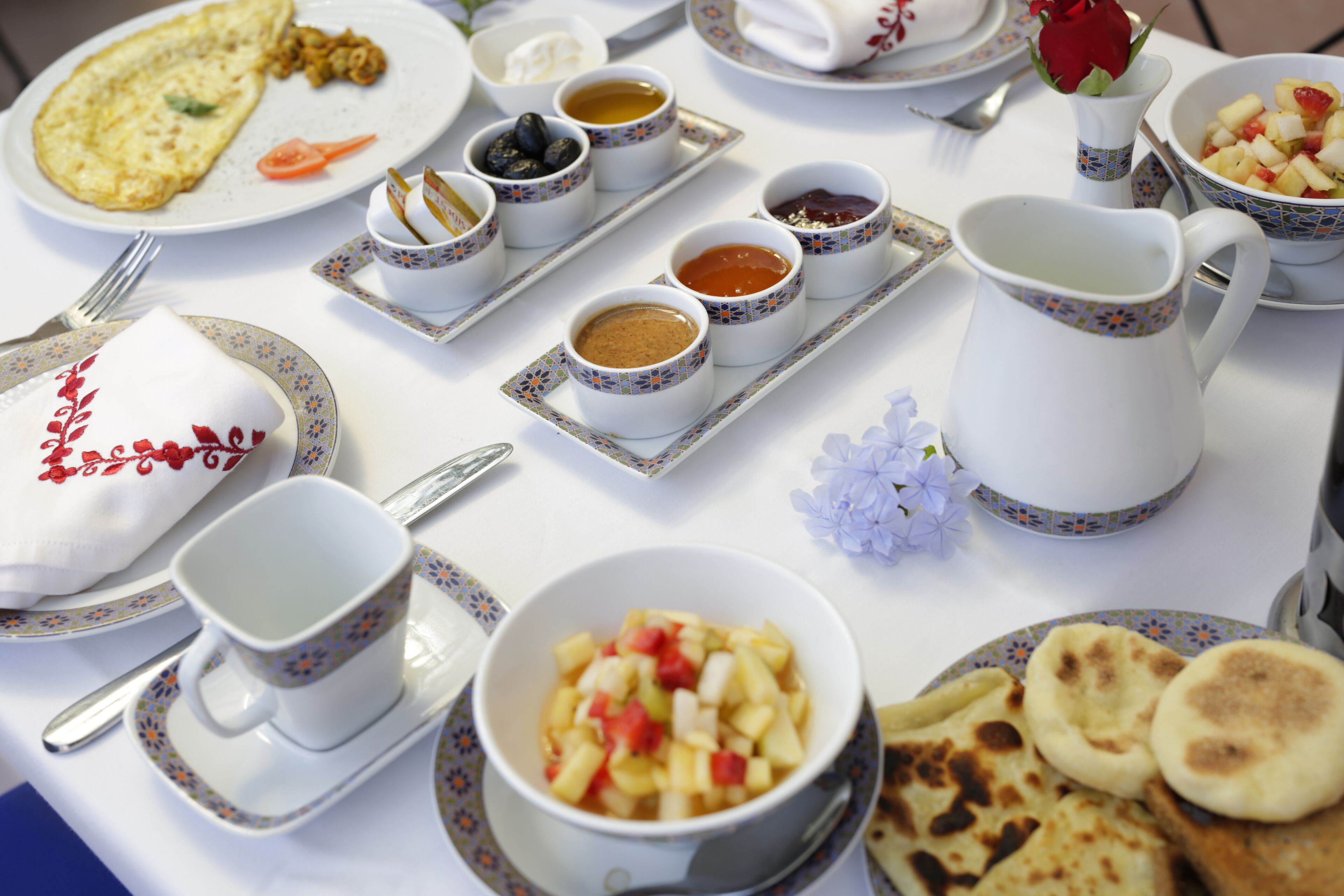 A table set with various dishes including an omelette, fruit, and multiple small bowls of sauces.
