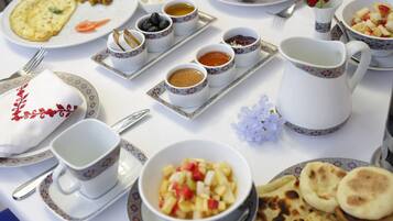 A table set with various dishes including an omelette, fruit, and multiple small bowls of sauces.