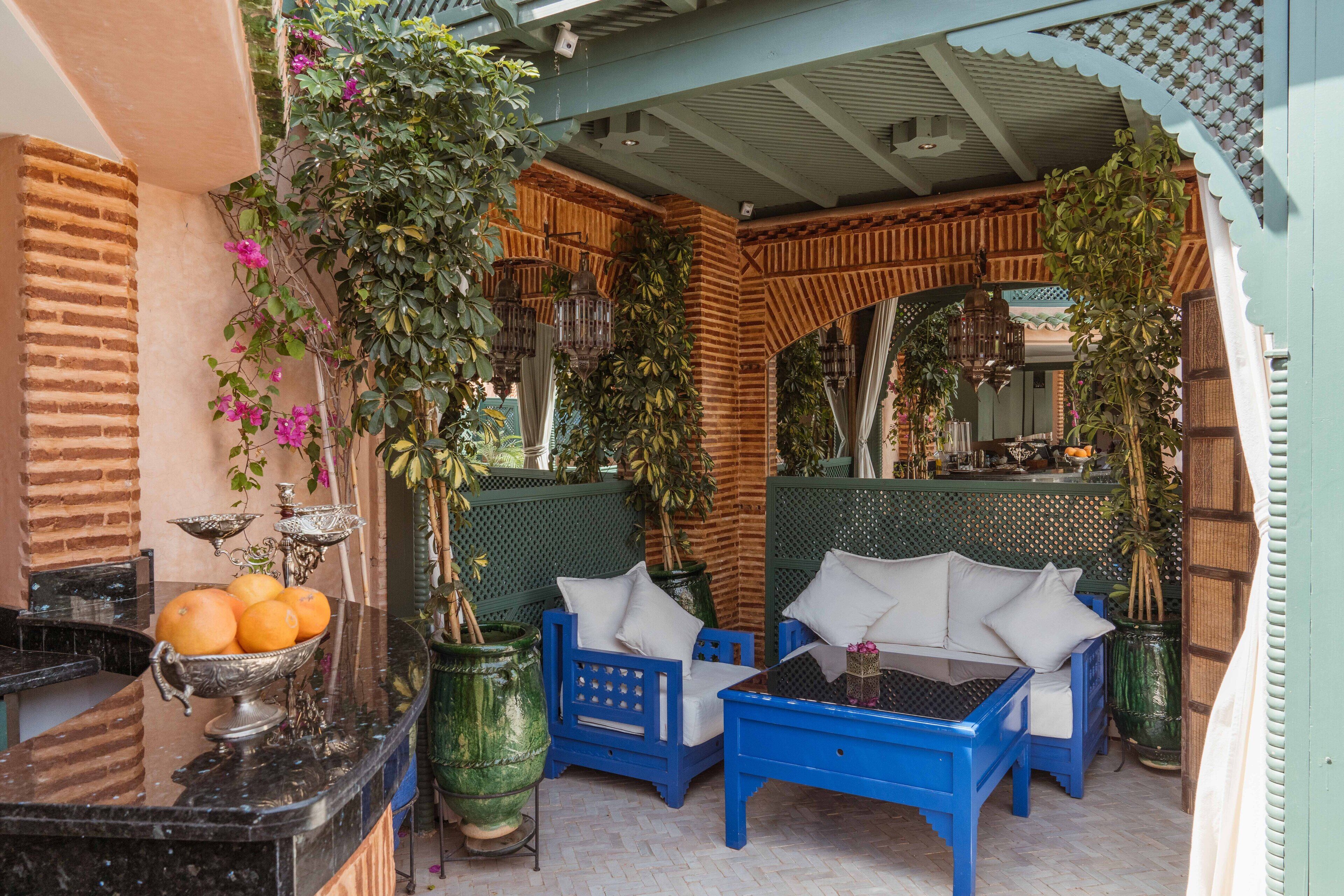 A cozy outdoor seating area with blue furniture and a decorative metal bowl of oranges.