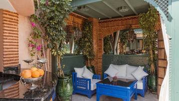 A cozy outdoor seating area with blue furniture and a decorative metal bowl of oranges.