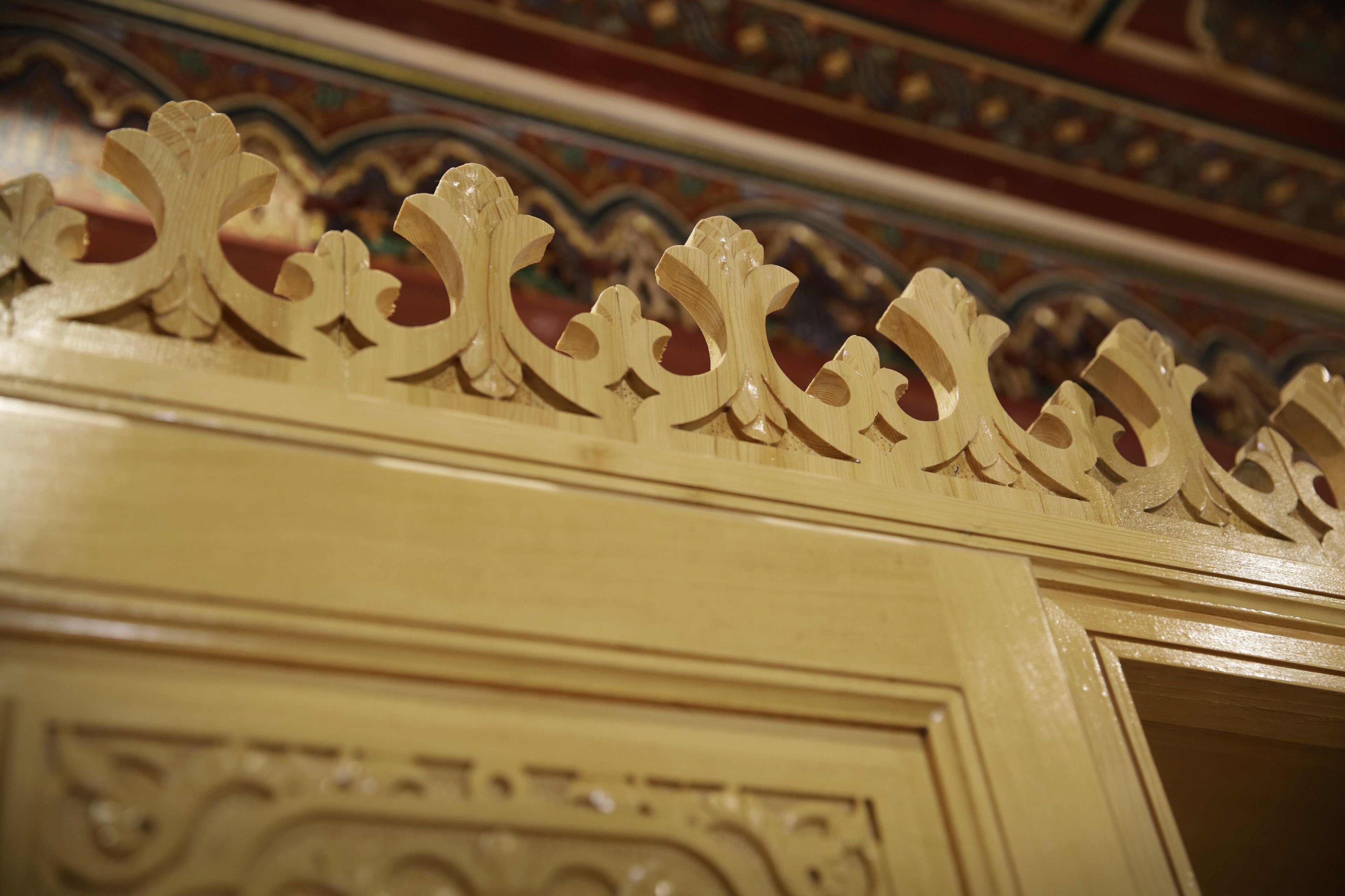 A close-up of a decorative wooden panel with intricate carvings, part of a building's interior architecture.