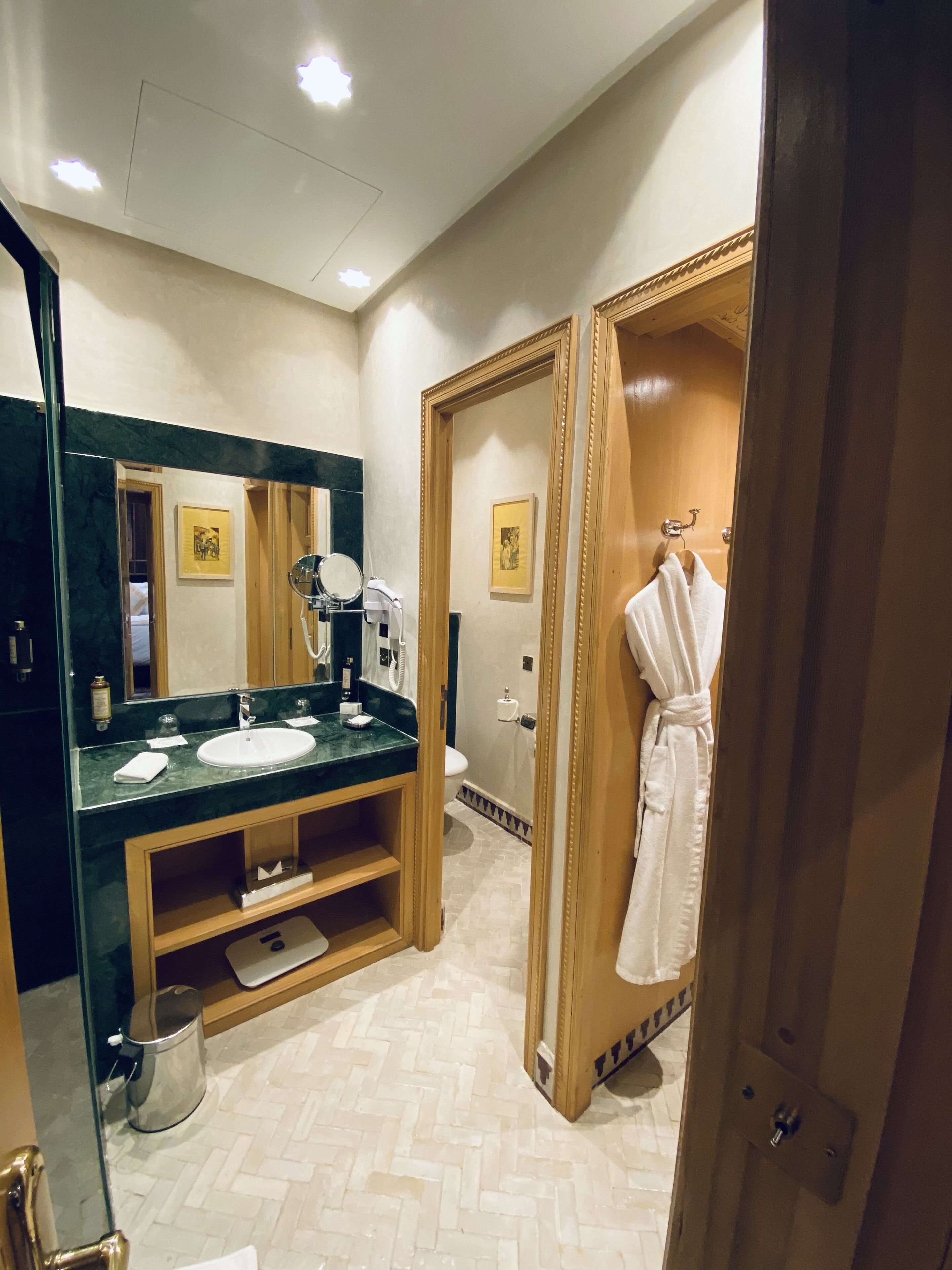 A modern bathroom with a large mirror, a sink, and a robe hanging on a door.