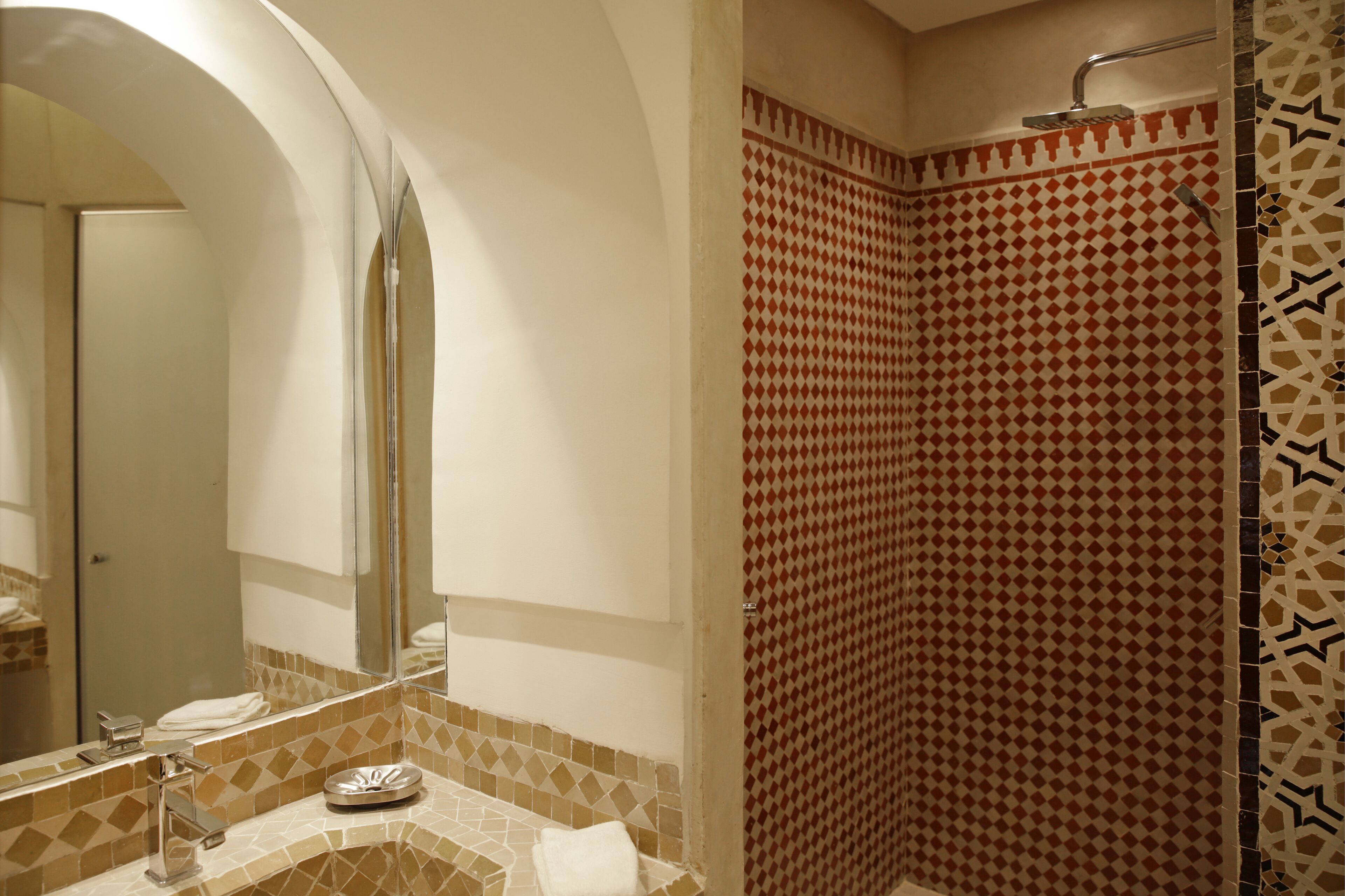 A bathroom with a tiled shower, a sink with a mirror, and a towel rack.