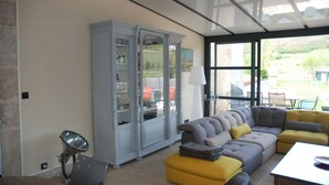 Una sala moderna con un sofá seccional gris, un taburete amarillo y un mueble grande.